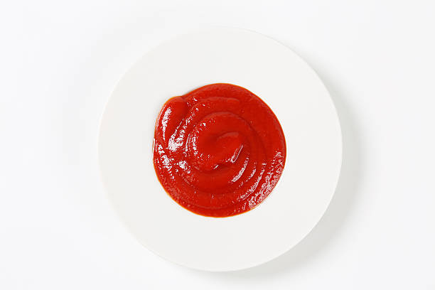 istock Looking down at dollop of ketchup on a white plate on white 464480117