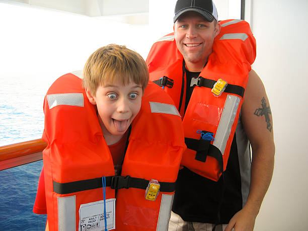 férias: pai, filho divertido navio de cruzeiro treinamento de segurança.  coletes salva-vidas. - life jacket equipment safety jacket - fotografias e filmes do acervo