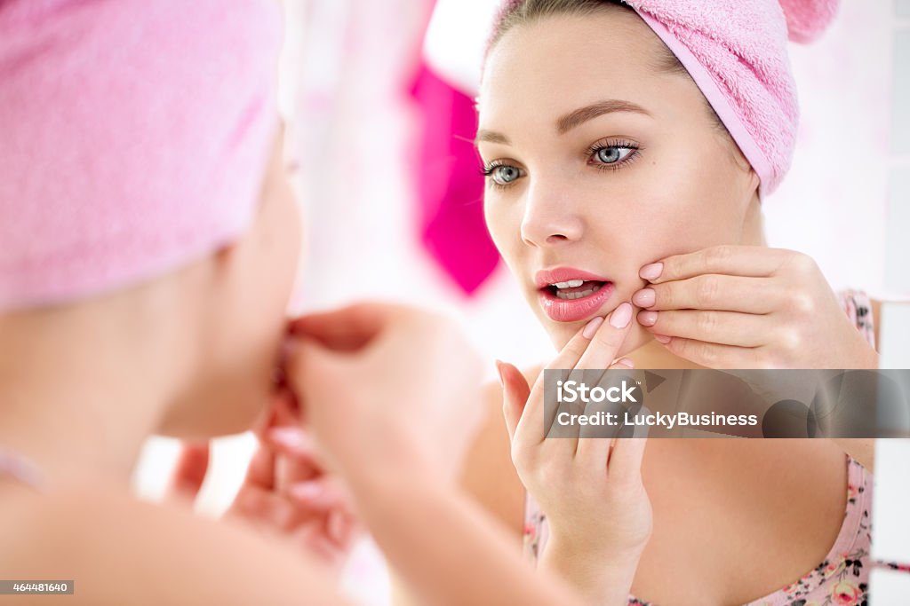 Young teenage girl  with pimple Young teenage girl  looking pimple on her face in a mirror, concept problem on skin Pimple Stock Photo