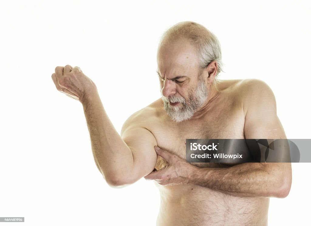 Senior Adult Man With Arm Or Shoulder Pain A senior adult man with arm or shoulder pain is looking down toward his right arm and touching his bicep with his left hand to try to alleviate the pain. He works out regularly at an exercise fitness gym, so sometimes is sore here and there afterwards. Cut Out Stock Photo