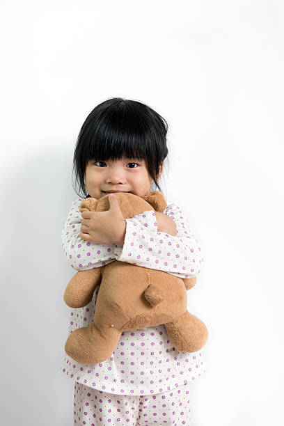 Smiling child in pyjamas holding teddy bear