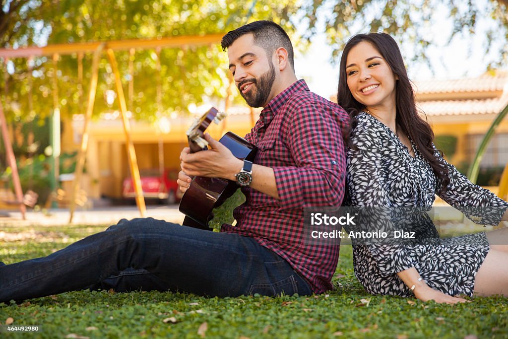 Listening to my boyfriend play Beautiful young woman enjoying the music her boyfriend plays in the guitar 2015 Stock Photo