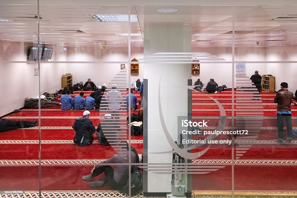 Muslim men praying in prayer room Doha, Qatar - February 18, 2014: Muslim men praying in one of 13 prayer rooms at Doha International Airport, the only commercial airport in Qatar. 2015 Stock Photo