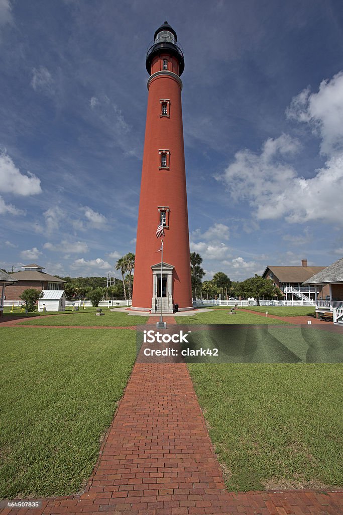 Ponce Inlet Lighthouse Red brick, tall Ponce Inlet Lighthouse, walk way and green grass in foreground against blue sky Ponce Stock Photo