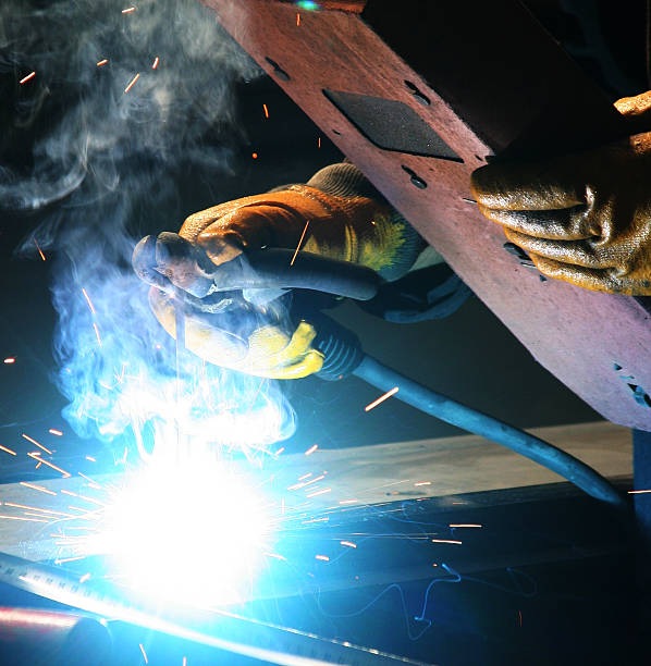 Welder welds using light shield and protective gloves Welding  welder engineering construction bright stock pictures, royalty-free photos & images