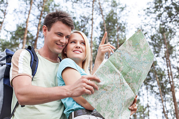 istock Young hiking couple holding map with woman 464544677