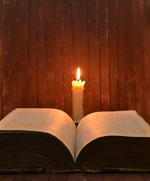 istock Burning candle with open book on desk 464549272