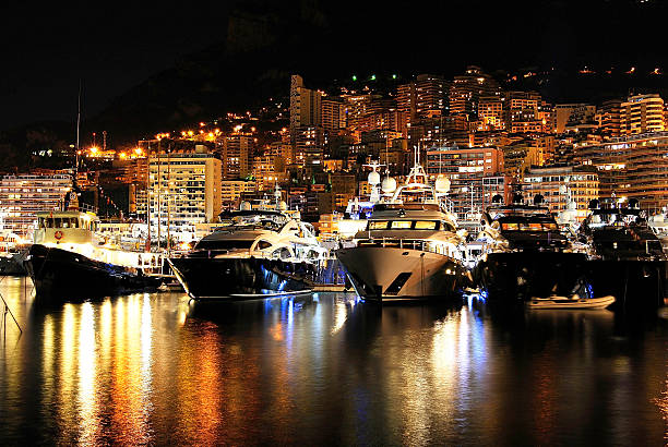 Magnificent landscape of Monaco at night from the sea luxury colorful boats and buildings in Monaco at night.  monaco stock pictures, royalty-free photos & images
