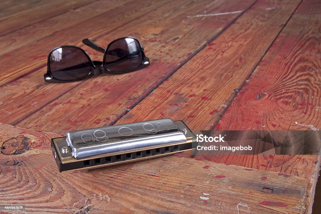 Got the BLUES? Harmonica foreground on rustic wood table with glasses. Blues Music Stock Photo