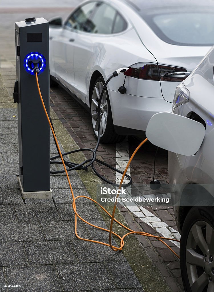 Recharging in the street Recharging two electric cars  in an urban street from a special station on the sidewalk Electric Car Stock Photo