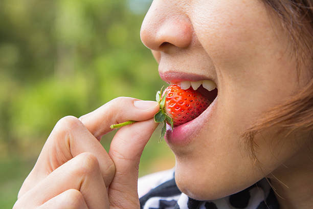istock Pretty young female eating fresh strawberry 464569834