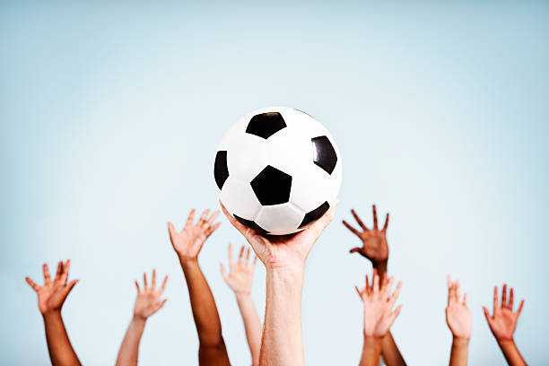 istock Many hands supporting championship soccer ball against sky 464570479