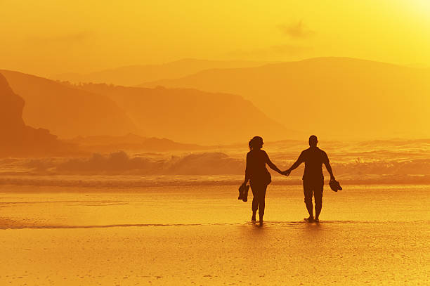 istock couple walking on beach at sunset 464574220