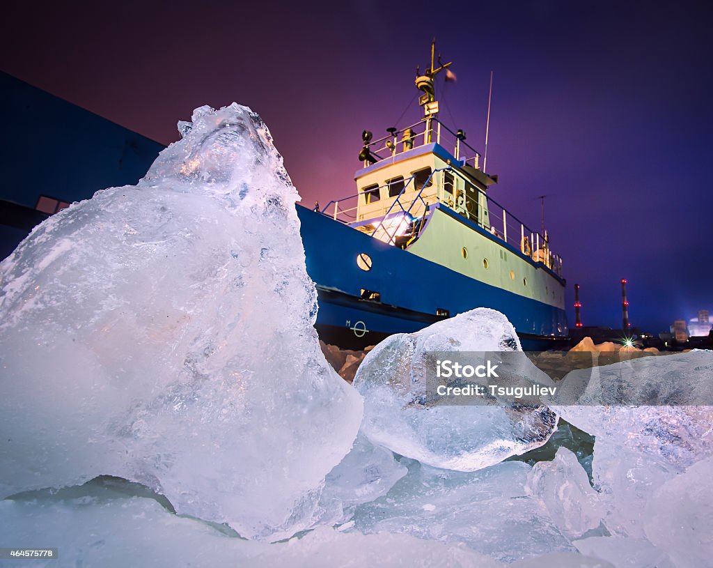 An iceberg with a ship trying to go through The Icebreaker ship trapped in ice tries to break and leave the Antarctica Stock Photo