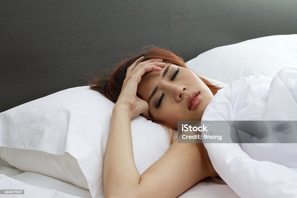 sick woman on bed with her hand at forehead sick woman on bed, symptom of cold, flu, insomnia, stress, headache, hangover, dizziness Adult Stock Photo