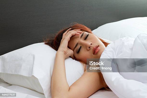Sick Woman On Bed With Her Hand At Forehead Stock Photo - Download Image Now - Adult, Adults Only, Bed - Furniture