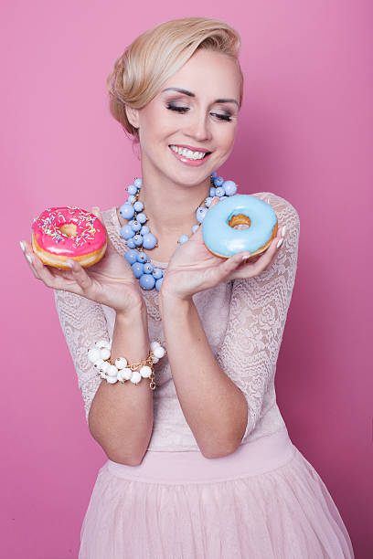 istock Nice young women hold colorful donuts. Soft colors 464581984