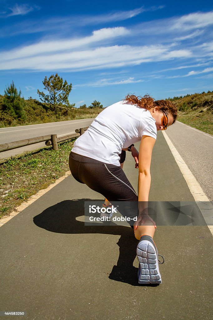 Athletic woman suffering pain in leg calf by cramp Back view of athletic young woman with sportswear suffering pain in her leg calf by a muscle cramp on a training. Sport injuries concept. 2015 Stock Photo