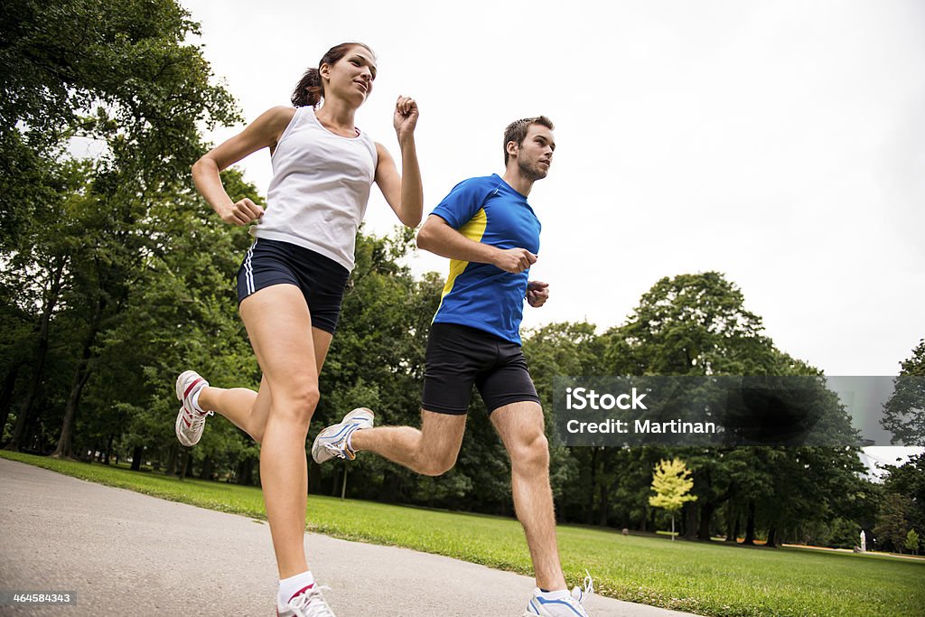 Jogging together - sport young couple Low angle photo of young couple  jogging outdoor in park Running Stock Photo