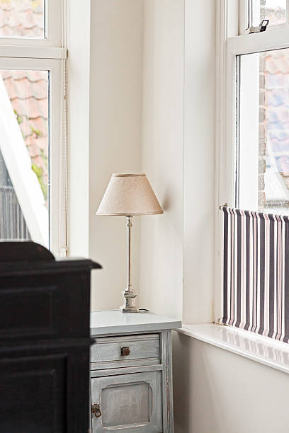 istock Lamp on white bedside table in bright hotel room. 464584665