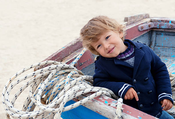 Little boy playing in the old fishing boat