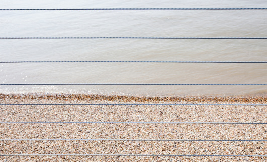 River Thames and Shingle beach behind wire rope fence