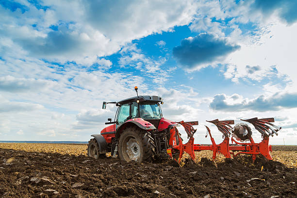 Farmer plowing field in red riding tractor Farmer plowing stubble field with red tractor field stubble stock pictures, royalty-free photos & images