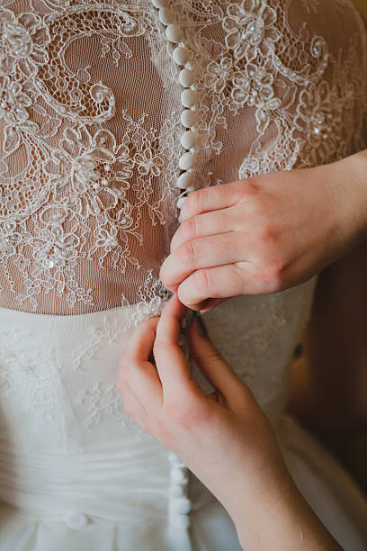 istock bridesmaid's hands buttoning wedding dress 464597632