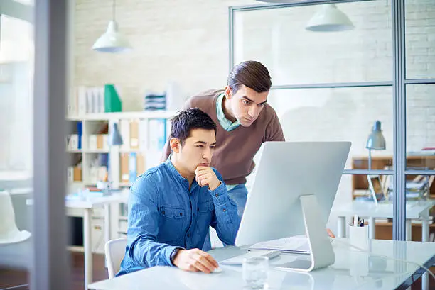 Two thoughtful office workers looking at computer monitor