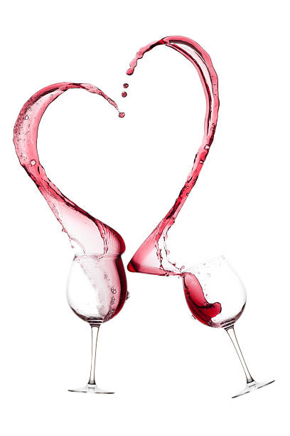 istock Two wine glasses with pink wine spilling out to form a heart 464612183