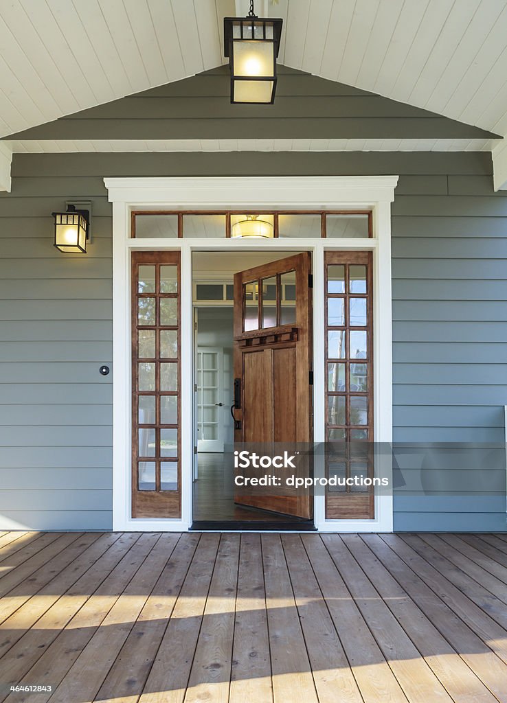 Front porch of blue-gray house with open front door Vertical shot of wooden front door of an upscale home with windows Door Stock Photo