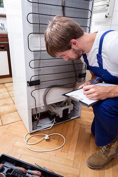 istock Handyman bends down, looks at the fridge 464618212