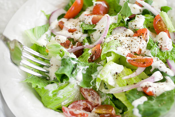 House Salad A house salad containing leafy greens, grape tomatoes, red onions, ranch dressing, and fresh cracked black pepper ranch dressing stock pictures, royalty-free photos & images