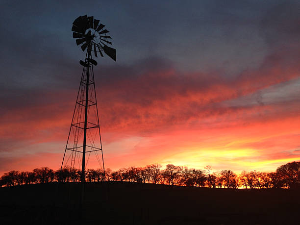 istock Windmill and trees in silhouette against a colorful sunset. 464619100
