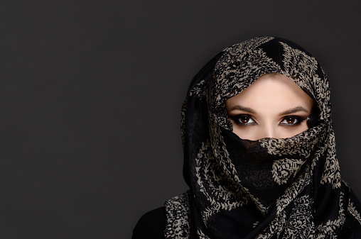 Beautiful Woman in Middle Eastern Niqab veil on grey background