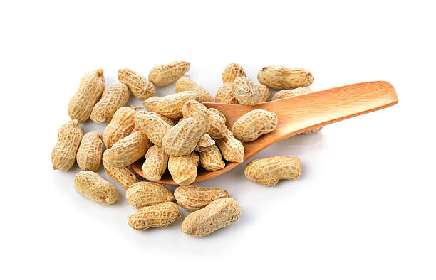 istock Peanuts in wooden spoon on white background 464622666
