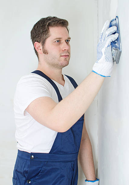 istock Male plasterer in uniform polishing the wall. 464627507