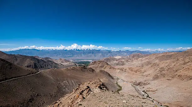 A shot on Khardungla Pass; the highest motorable road in the World. The road on the left leads to Leh, the capital city of Ladakh, India. The small stream on the lower right is the melted snow water coming down the mountain to feed the green valley in the distance.