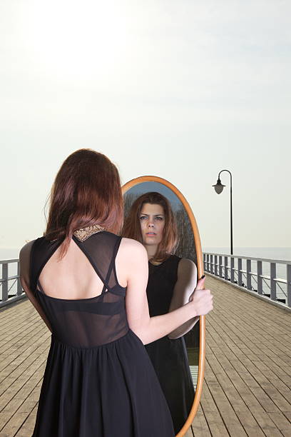 istock thoughtful woman looks at the reflection in mirror 464628089