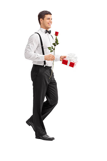 istock Elegant guy walking with a rose and a present 464639064