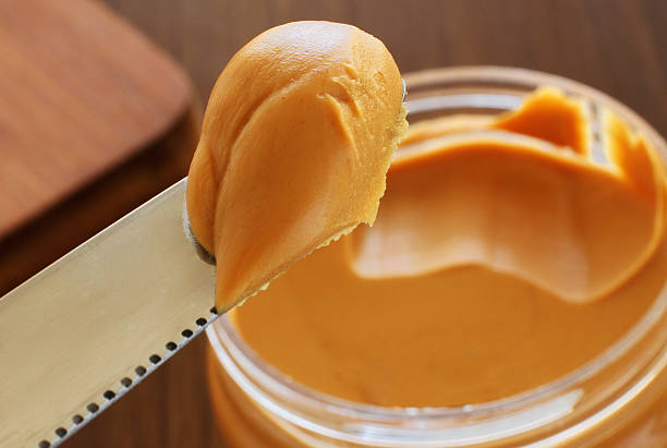 Peanut butter jar and knife holding some of it Peanut Butter on a Knife spreading photos stock pictures, royalty-free photos & images