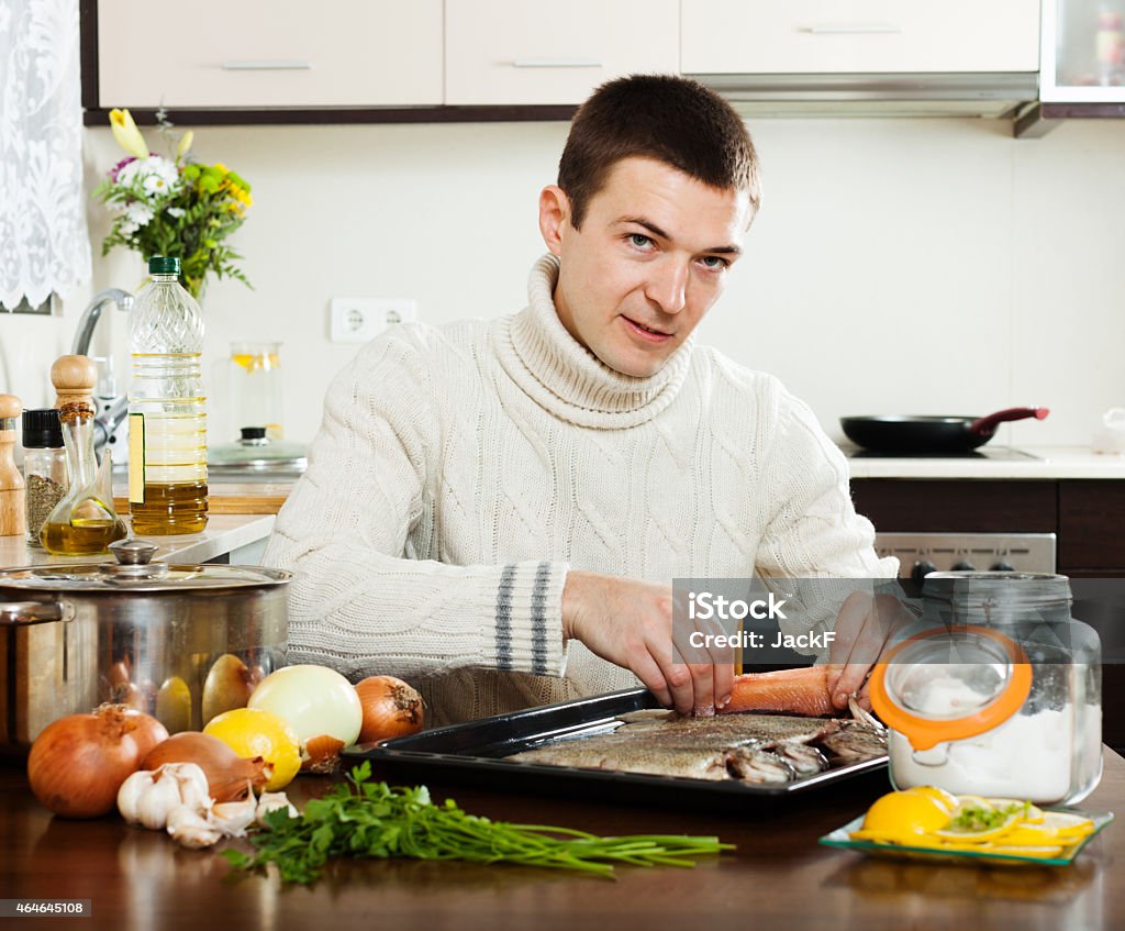 man salting fish on baking sheet man salting fish on baking sheet at home kitchen 2015 Stock Photo