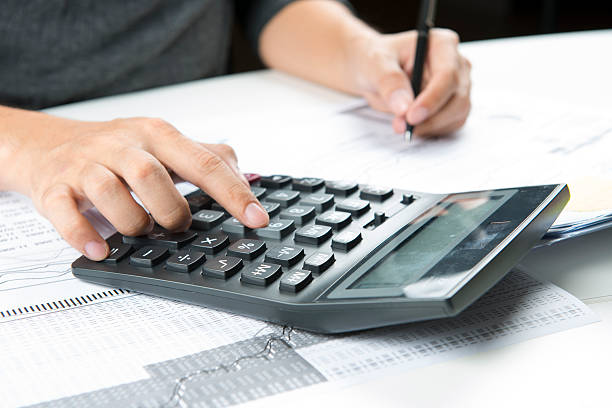 istock Close-up of calculator with hands taking notes 464645198