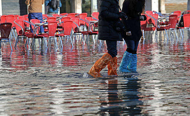 menschen mit leggins und stiefeln bei flut in venedig - people winter urban scene chair stock-fotos und bilder