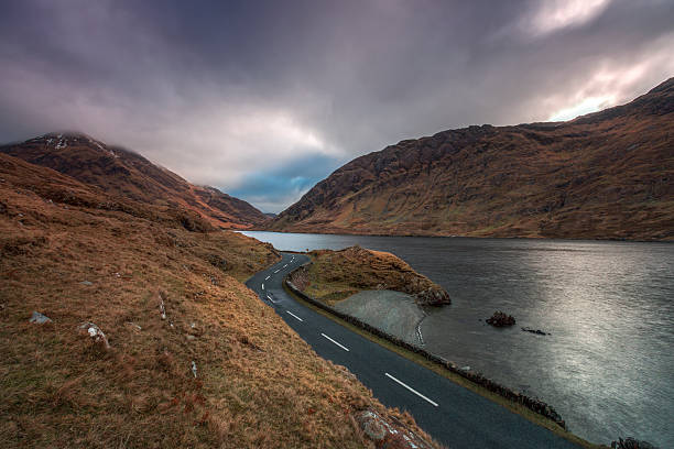 istock road through a mountain pass by a lake 464650074