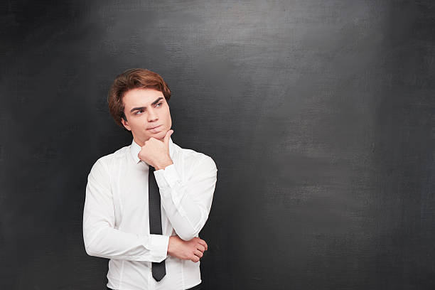 istock Confused young man on chalkboard background 464654748