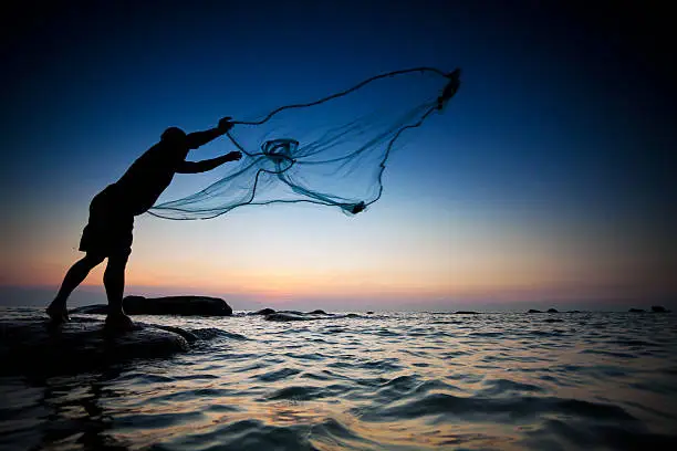 throwing fishing net during sunset , thai