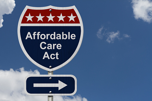 Affordable Care Act Sign, A red, white and blue highway sign with words Affordable Care Act and an arrow sign with sky background