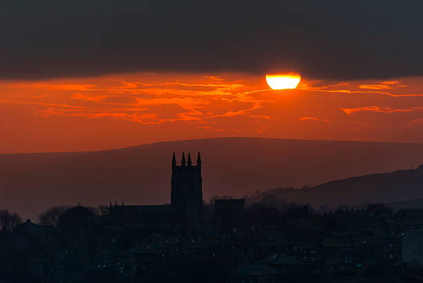 A warm winter sun sets over the hills of the South Pennines silhouetting the Church in the Yorkshire village of Heptonstall near to Hebden Bridge in Calderdale