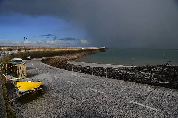 Wide angle image of  a pier just after a hailstorm moving over the sea.